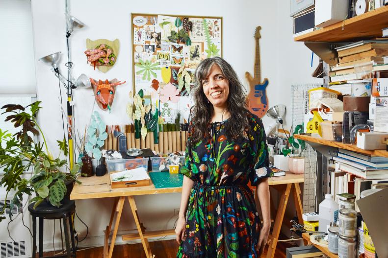 Woman Smiles To Camera Surrounded By Paper Art In Home Studio