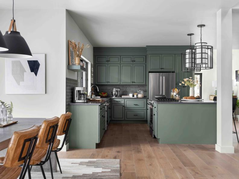This inviting kitchen has cozy neutral gray walls, and sage green cabinets with raised panel doors and organizational tools inside. “There are so many evergreens up here, we loved the tying in of the green kitchen cabinets to the green spaces outside,” says designer Brian Patrick Flynn. 
