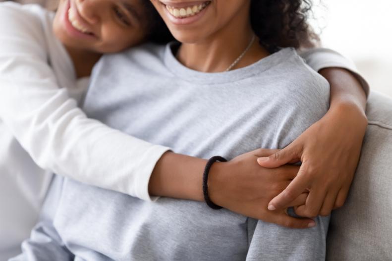Cropped close-up image smiling adolescent daughter cuddling mom at home celebrating gratitude.