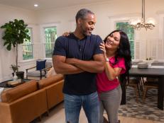 As seen on HGTV’s Married to Real Estate, hosts Egypt Sherrod and Mike Jackson pose for a picture in front of the redesigned family room and dining area of the Posts's newly remodeled home. (Reveal)