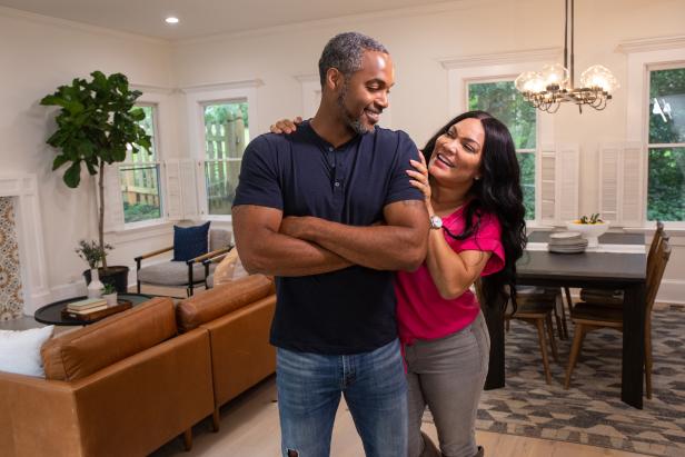 As seen on HGTV’s Married to Real Estate, hosts Egypt Sherrod and Mike Jackson pose for a picture in front of the redesigned family room and dining area of the Posts's newly remodeled home. (Reveal)