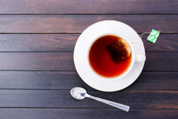 Top view of hot tea in a teacup placed on a vintage wooden floor.