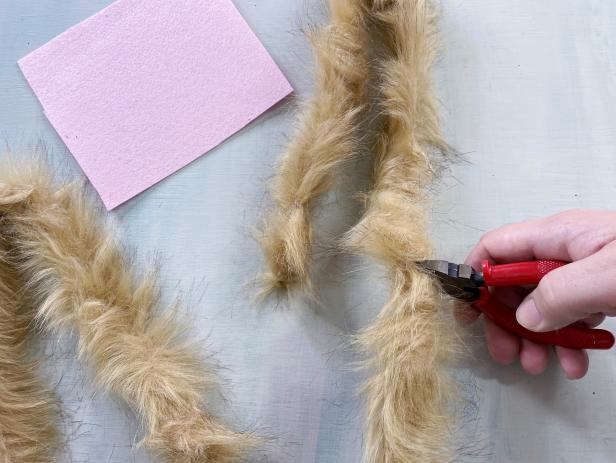 Measure and cut the fuzzy pipe cleaner into two 20’’ pieces. Bend them each in half and manipulate them to mimic the shape of bunny ears. Out of felt, cut two long, almond-like shapes for the inside of the ears. Use a glue gun to add a slight amount of hot glue around the edge of the felt. Then press the felt into the center of the pip cleaner.