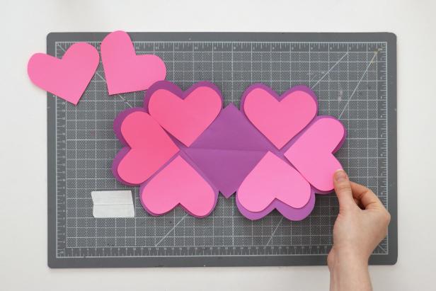 Trace one heart onto scrap paper and cut it out. Cut off about ⅛” all the way around to make a slightly smaller heart pattern. Trace this onto a second color of paper and cut out 8 hearts. You can also cut out a square that fits in the center of the card.