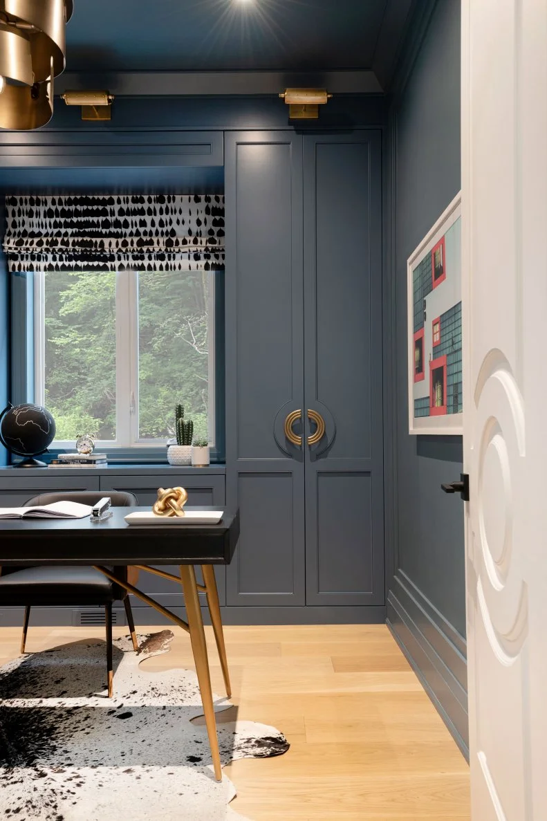 This home office features gray blue paint and black and white rug.