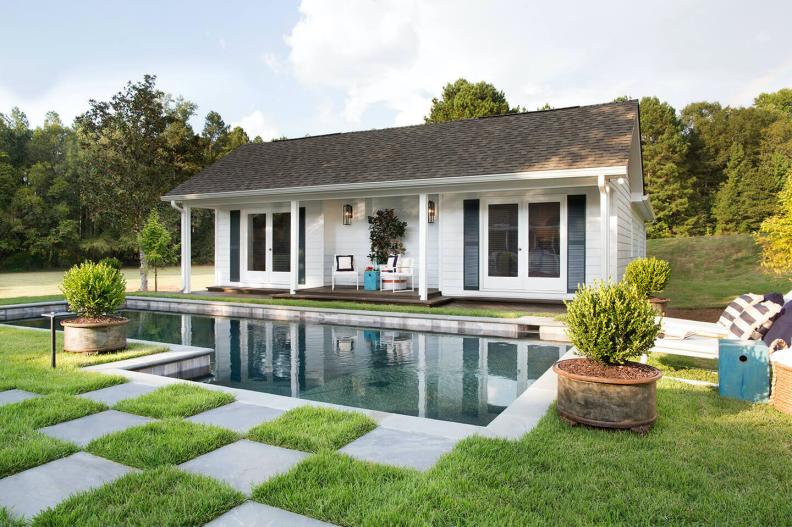 Small guest house in front of pool with checkerboard pavers.