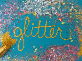 Word Glitter Spelled Out on Blue Paper, Colorful Glitter All Around 