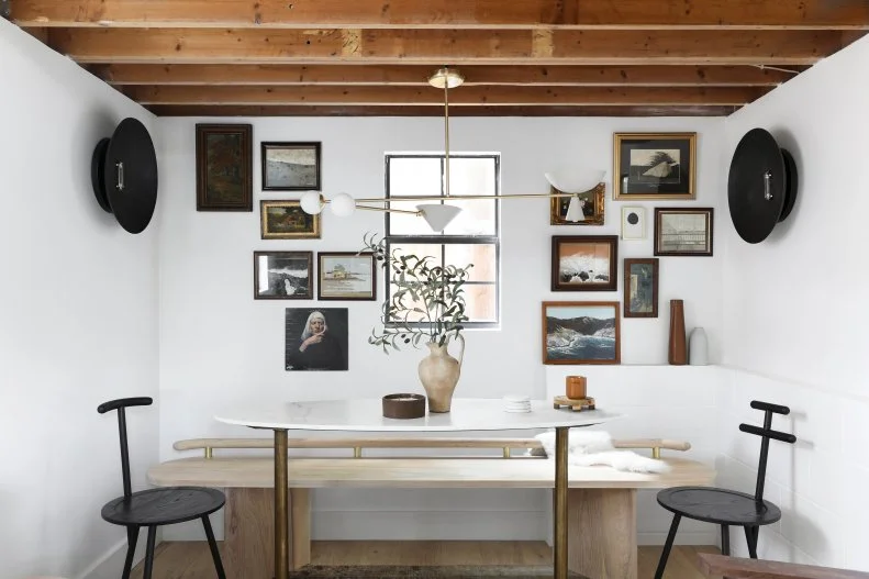 Small dining area with art and photos surrounding bench and table.