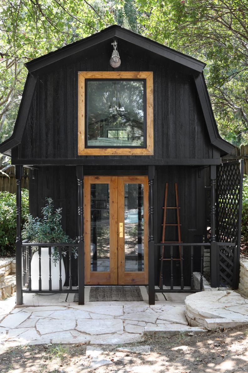 Black tiny house with neutral window and doors.