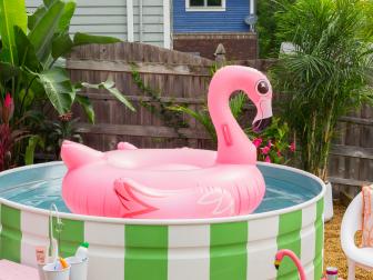 Pink Flamingo Float In Stock Tank Pool with Stripes, Palms in Yard