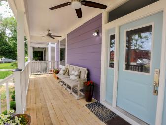 The porch of the renovated home is shown as seen on HGTV's Good Bones. The exterior of the home is purple with white trim.