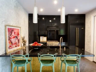 Kitchen with wall of black cabinets and eclectic blue bar stools. 