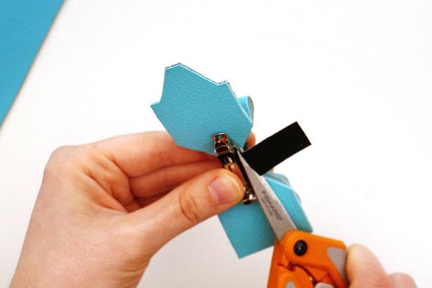 Add hot glue to the end of the black rectangle. Glue the rectangle so it covers the bottom of the hair clip. Use a toothpick to help press it into place. Let dry.Add more glue to the center of the bow and wrap the rectangle around. Let dry. Add glue to the next section of the rectangle and feed it back under the hair clip, pulling it tight and pressing it into place with a toothpick. Trim the excess fabric.