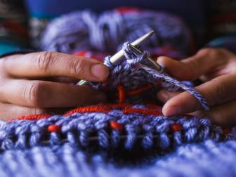 Woman's Hands Form Stitches With Knitting Needles And Yarn