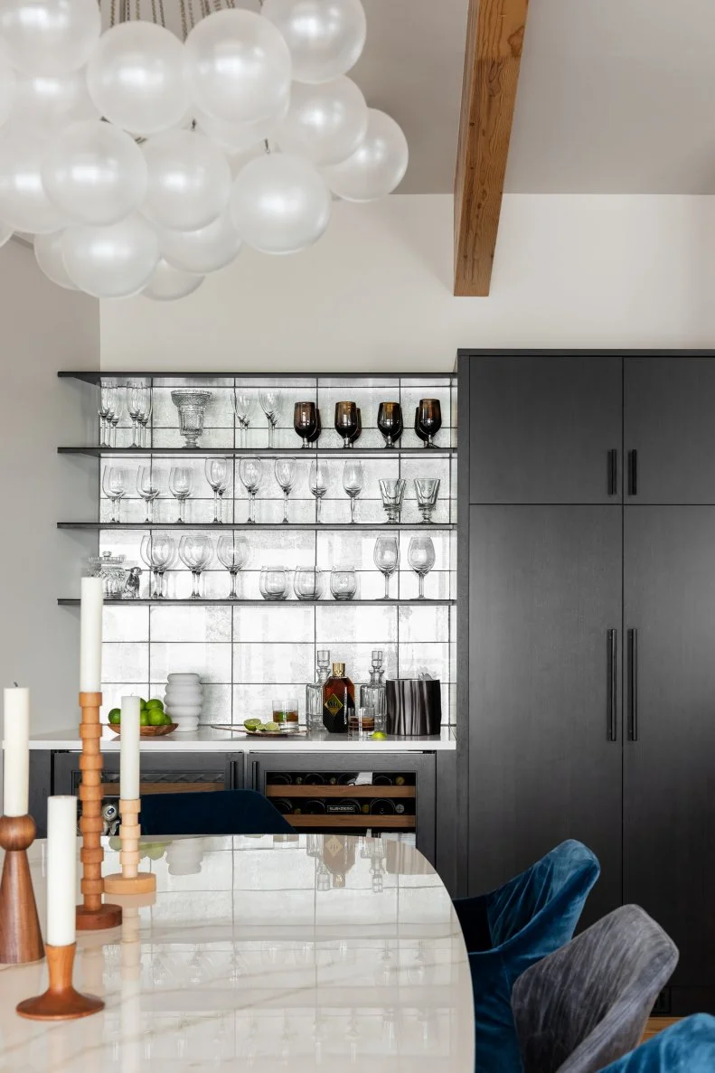 Mirrored bar with white dining table and floating shelves.