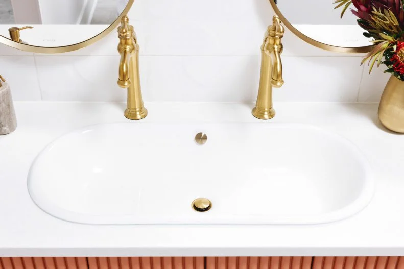 The vanity’s two white elongated capsule sinks have a gently curved, organic shape. The distinctive sinks are made of enameled cast iron, with a smooth enameled interior.