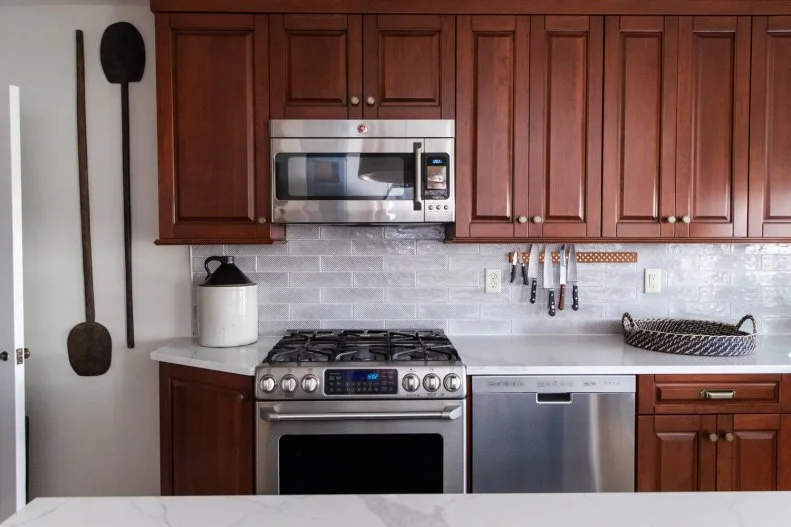 Kitchen with red wood cabinets, white tile and white counters.