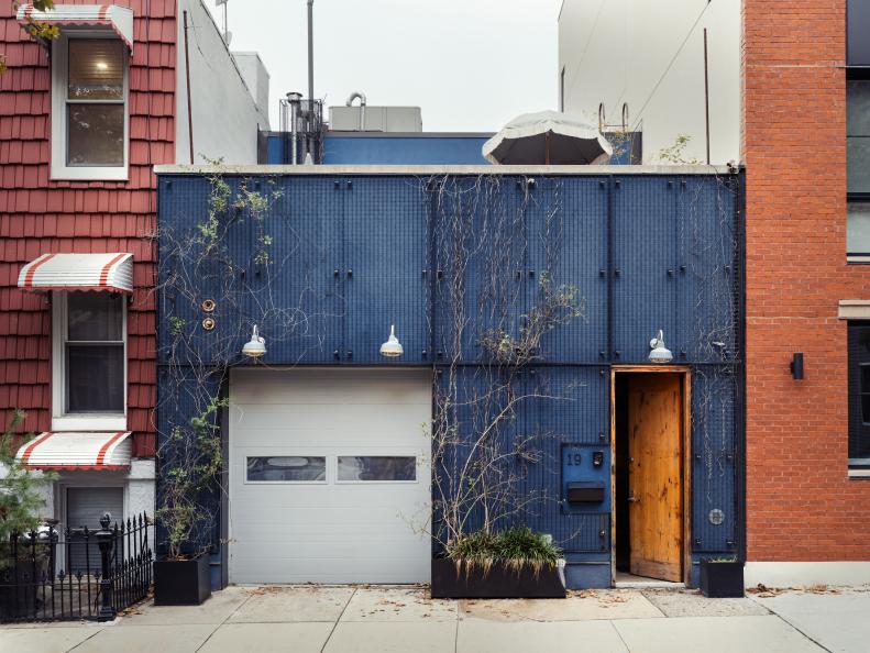 A blue, industrial-looking facade with white garage and wooden door