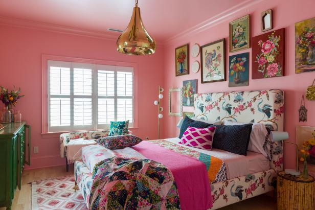 A guest room with a bed, a gallery wall, and pink walls and ceiling