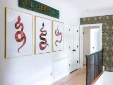 Three large pink snake prints hang in a hall at the top of stairs. 