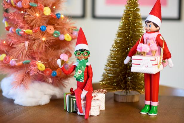 Two toy elves with miniature cotton candy cones. 
