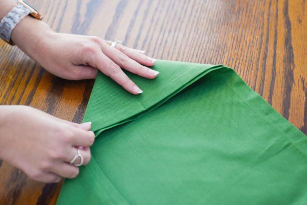 Continue this envelope napkin folding technique by folding the edges toward the middle.