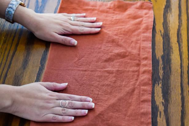 The first step toward creating this Thanksgiving napkin fold is to fold the napkin in half.