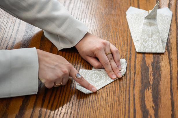 The next step in creating this Thanksgiving turkey paper napkin fold is to fold the side back and over.