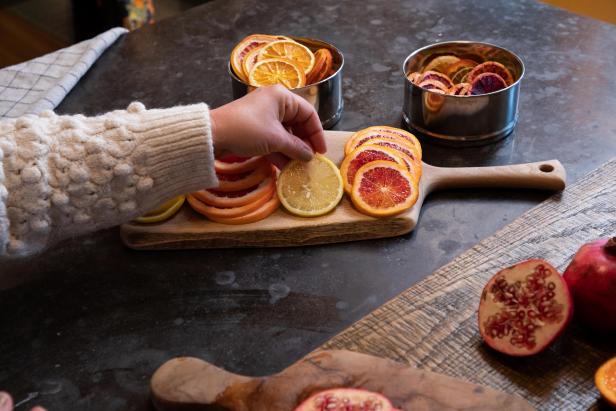 The next step in drying citrus slices for holiday decor is to arrange the slices on a cutting board to prepare for drying.