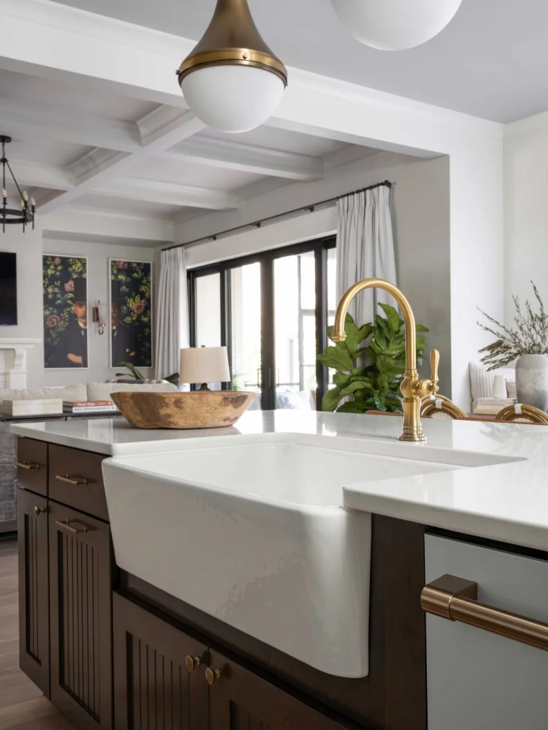 The kitchen’s farmhouse sink has a large, single bowl that accommodates large pots and pans, and a sleek apron that brings a modern, clean-line aesthetic. The sink’s faucet displays vintage style, with a high-arc spout and turned lever handle. 