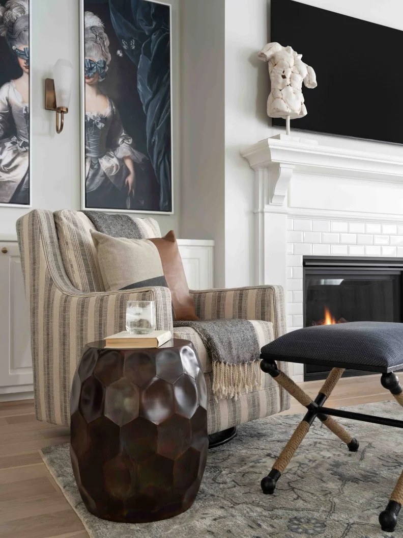 Sit back and enjoy a good book in one of the two accent chairs by the fireplace. The chairs are paired with coastal-style ottomans, and accent stools with a honeycomb design and burnt copper-tone finish.