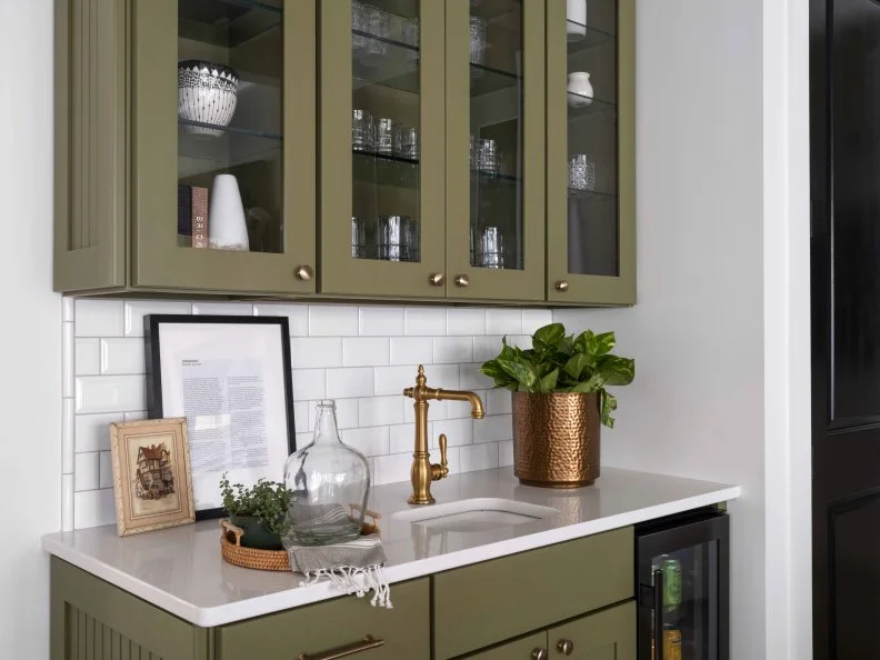 A white subway tile backsplash behind the wet bar protects the living room wall, and creates a clean look. The tile backsplash also helps define the bar area, and makes it a defined destination in the living room.