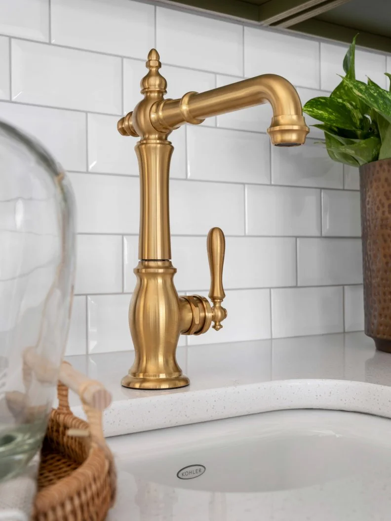 An undermount white bar sink includes a Victorian-inspired bar sink faucet. The faucet has an elegant column design, with convenient swing spout, single lever handle, and brushed brass finish.