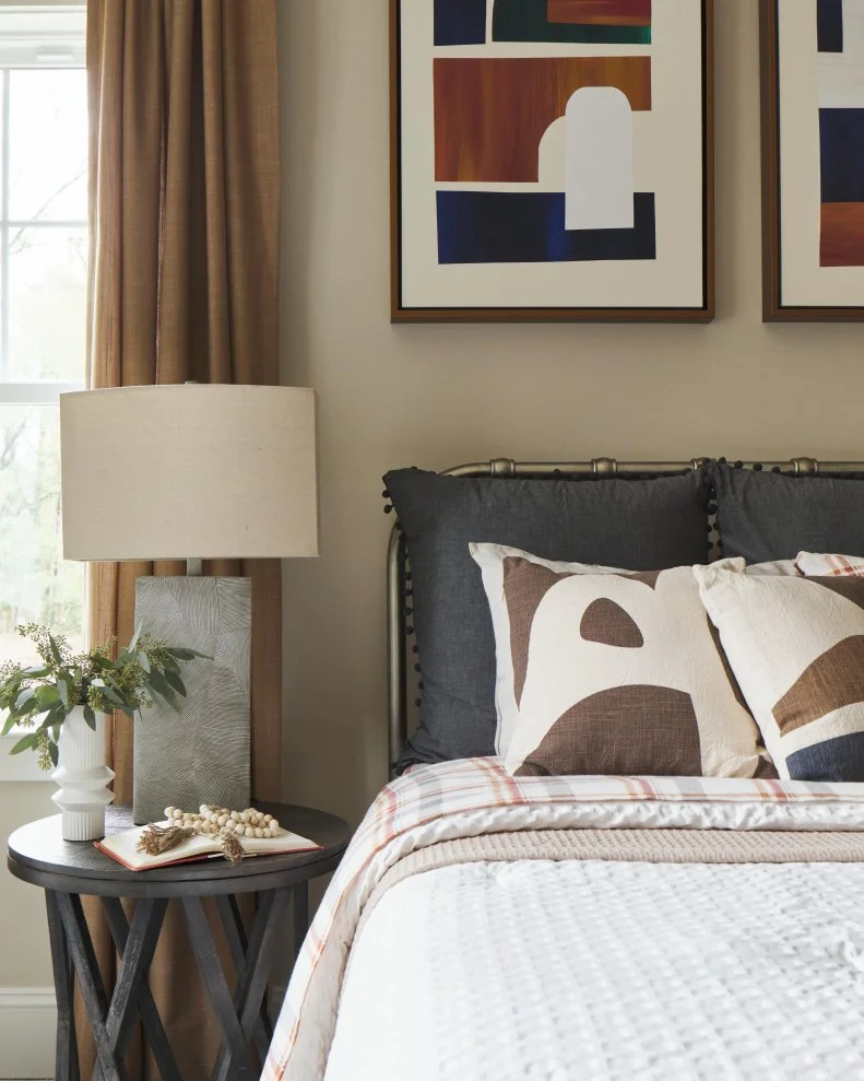 A small side table creates space for evening reading or glass of water while a table lamp adds soft lighting with a modern brushed metal base.
