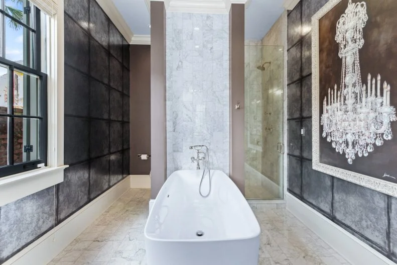 Neutral bath suite with large chandelier painting and soaking tub.