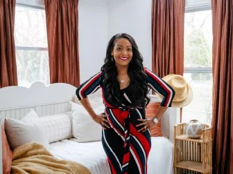 As seen on HGTV's Bargain Block, Shea Hicks-Whitfield poses in the primary bedroom before a tour of the Hampton House.