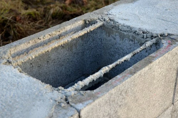 construction of a concrete wall from concrete blocks filled inside with reinforcing steel and concrete. gray stepped wall of hollow bricks on the foundation of a house or fence