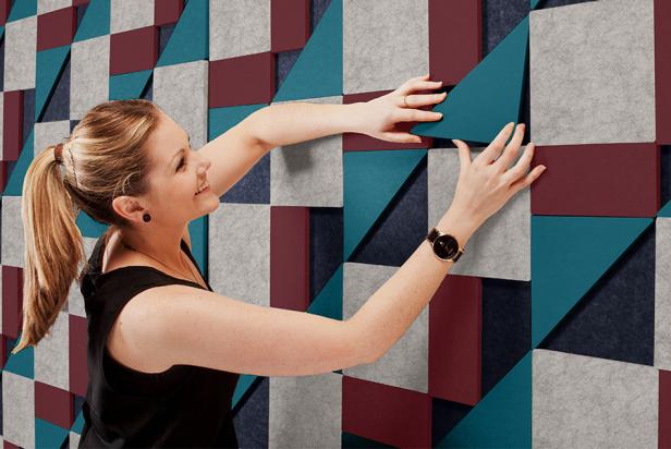 Girl assembling a soundproofing wall with sound absorbing tiles.