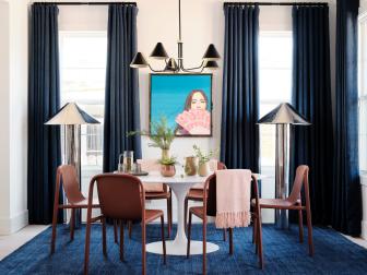 A large piece of original art, inspired by musician Kacey Musgraves, anchors the main wall of the dining area and brings life and personality to the space. Long, navy drapes frame the windows and draw the eye upward giving the room an elevated, spacious feel.