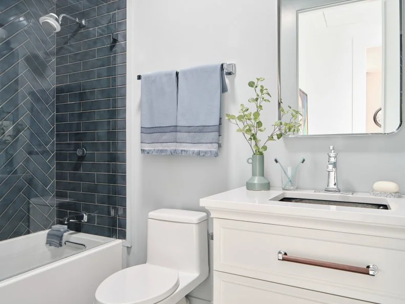 A 24-inch towel bar with distinctive, classic lines and olished Chrome finish holds faded blue linen striped hand towels that coordinate with the other beautiful blue design details in this streamlined space.