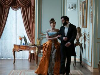 A man and woman arm and arm in a Victorian drawing room. 
