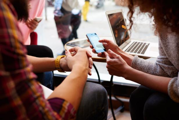 Close-up of woman on her cell phone while sitting with friends in hipster cafe interior