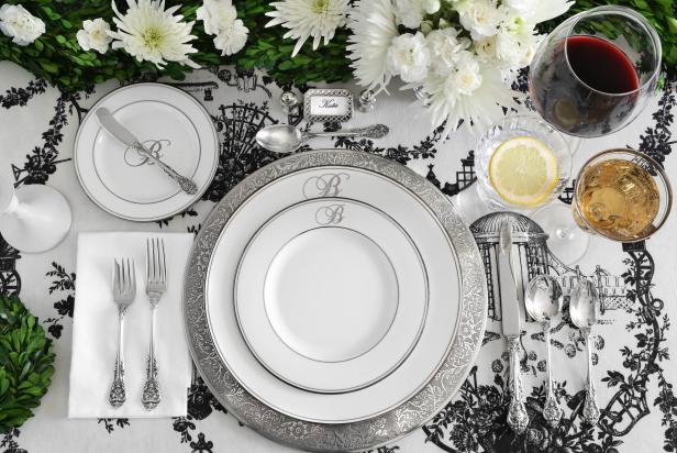 A formal table setting with dinner, salad and bread plates, flatware, wine and water glasses and a place card. 