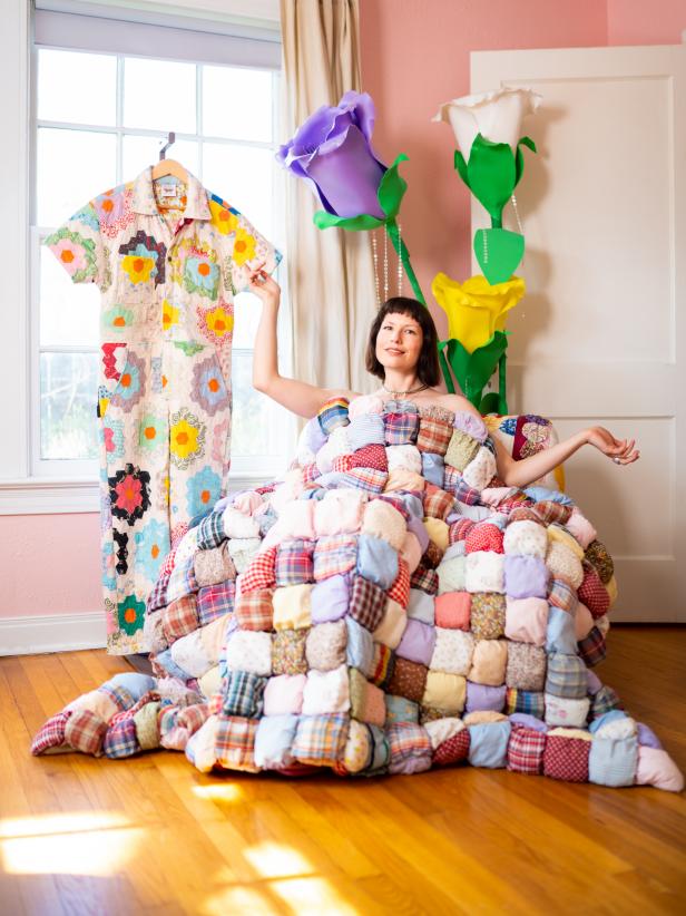 A woman sits in a chair underneath a puffy quilt.