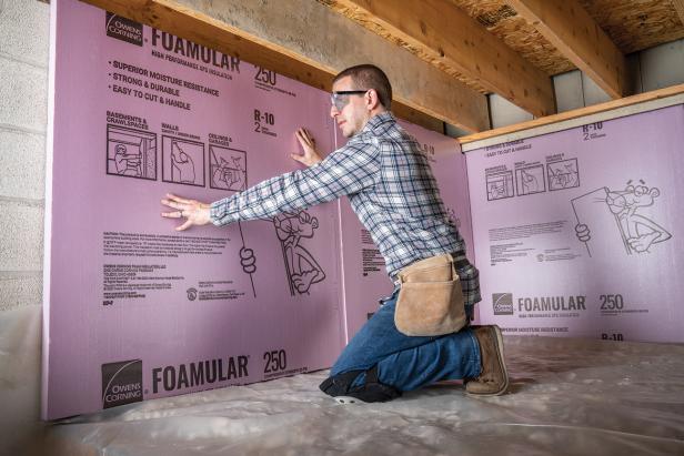 Person installing foam board insulation in a home's crawl space.