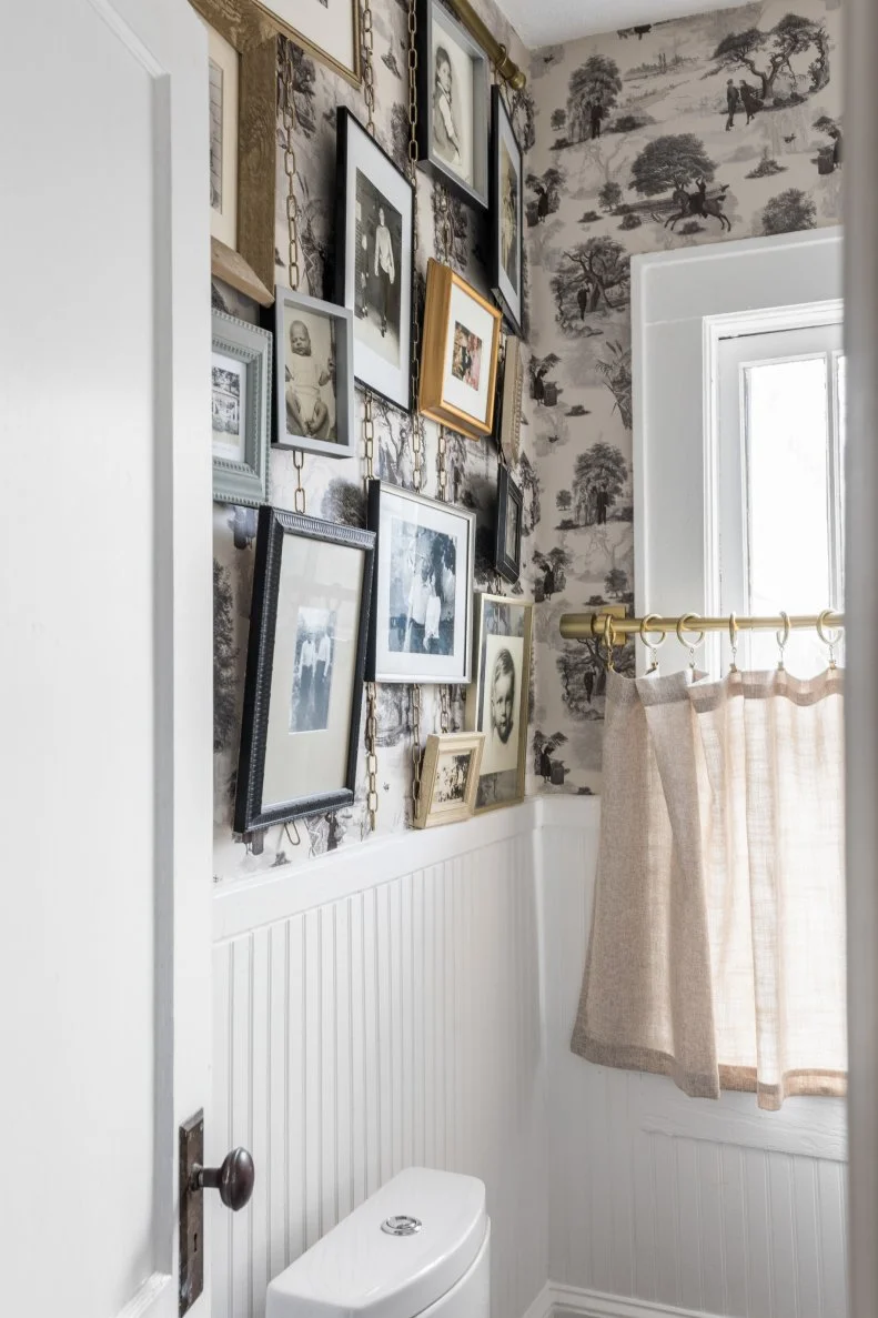 A metal picture hanging support from Ballard's allows vintage family photos to be hung and swapped out in this powder room next to the renovated kitchen. A cafe curtain allows the light in while maintaining privacy.