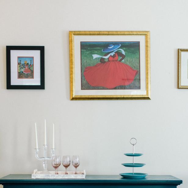 A painting of a woman in a red dress hangs above a buffet table.
