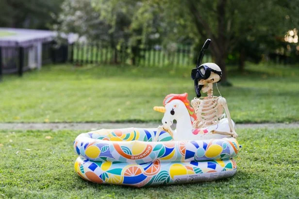 Skeleton sitting in a kiddie pool wearing a snorkel and floaties