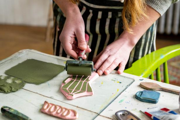 Woman uses brayer to apply green paint onto handmade rubber stamp