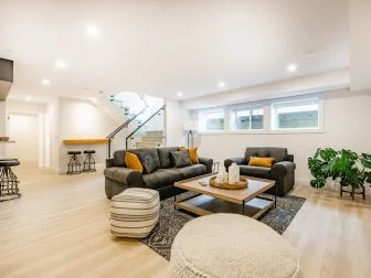 recreation party room with bar stairs with glass rails downstairs basement interior room with movie screen large grey sofa bohemian style